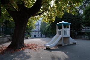 Miniature urban playground featuring a slide and surrounded by large trees in an empty area photo