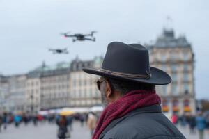 Wrangler directing flying bots in busy urban square at dusk photo