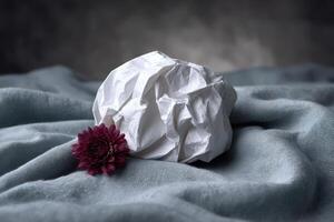 Crumpled napkin and flower on textured fabric background create an artistic arrangement photo