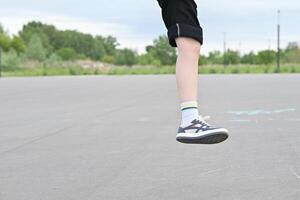 Child in motion, jumping with legs and shoes visible on an outdoor playground. photo