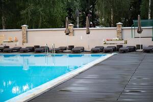swimming pool with metal ladder and lounge chairs around. photo