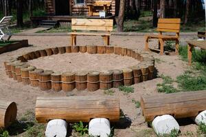 Circular seating area surrounded by wooden logs in a forest recreation space with benches for relaxation and gathering photo