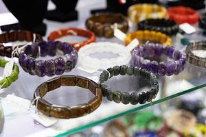 Assorted gemstone bracelets displayed on a glass shelf. Vibrant glass. photo