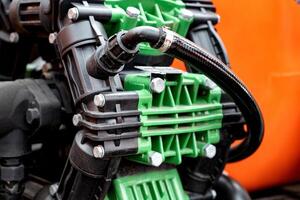 Close-up of industrial pump with green and black components, orange background. photo