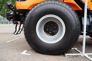 Close-up of a tractor wheel with orange rim on grassy ground. photo