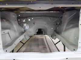 Symmetrical view of freshly primed car engine bay with detailed metalwork and structural panels, captured during a vehicle restoration process in professional workshop environment photo