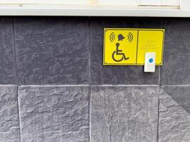 Accessible call button and Braille sign for wheelchair users on textured wall, symbolizing inclusive urban infrastructure and assistance for people with disabilities in public spaces photo