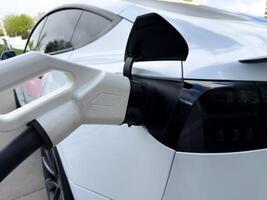 Close up of electric car being charged, highlighting the smooth aerodynamic curves and glossy surface, emphasizing premium design and future oriented automotive aesthetics photo