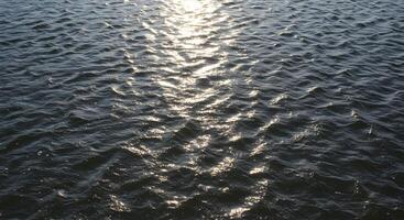 River surface texture with gentle waves shimmering across the water, ideal for backgrounds in websites, presentations, or nature-themed design projects. photo