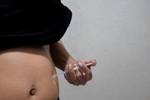 A man injecting himself with obesity medication. photo