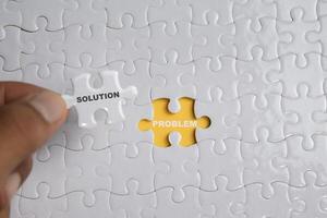 Hand holding piece of jigsaw puzzle with word solution problem. Business and finance concept photo