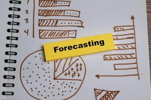 Concept of forecasting and charts write on sticky notes isolated on Wooden Table. photo