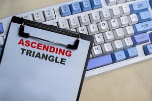 Concept of Ascending triangle write on clipboard isolated on Wooden Table. photo