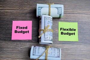 Concept of Fixed budget and flexible budget and dollars write on sticky notes isolated on Wooden Table. photo