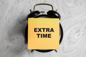 Concept of Extra time write on sticky notes isolated on Wooden Table. photo