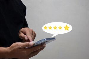 customer man hand pressing on smartphone screen with gold five star rating feedback icon and giving best score point to review the service. photo