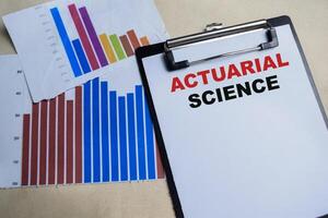 Concept of Actuarial science write on clipboard isolated on Wooden Table. photo