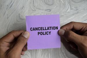Concept of cancellation policy write on sticky notes isolated on Wooden Table. photo