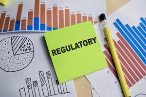 Concept of Regulatory write on sticky notes isolated on Wooden Table. photo
