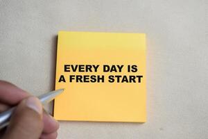 Concept of Every day is a fresh start write on sticky notes isolated on Wooden Table. photo