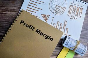Concept of profit margin and chart write on book isolated on Wooden Table. photo
