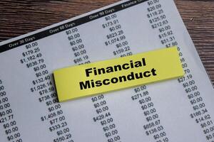 Concept of Financial misconduct write on sticky notes isolated on Wooden Table. photo