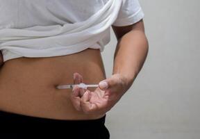 A man injecting himself with obesity medication photo