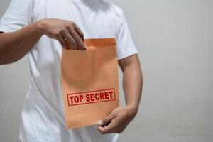 man holding sealed focus on top secret text document on gray background photo