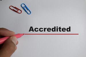 man writing text Accredited with marker on white background photo