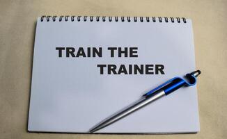 Concept of Train the trainer write on book isolated on Wooden Table. photo