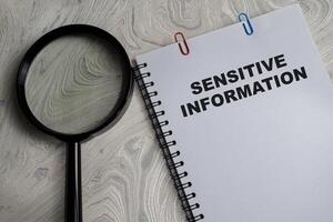 Concept of Sensitive information write on book isolated on Wooden Table. photo