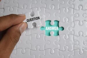 Hand holding piece of jigsaw puzzle with word Question and answer. Business and finance concept photo
