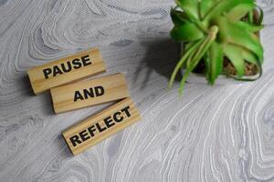 Concept of Pause and Reflect Symbol. Wooden block with words pause and reflect photo