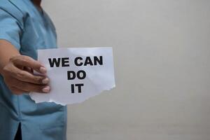 young man showing a piece of paper with the text we can do it written in it photo