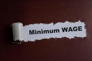 Concept of minimum wage Text written in torn paper photo