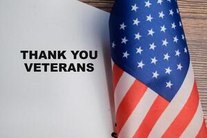 Concept of thank you veterans write on book and american flag isolated on Wooden Table. photo