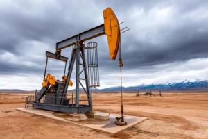 Pump jack extracting crude oil on a cloudy day with snowy mountains in background photo