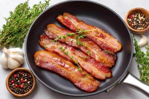 Fried bacon with thyme and spices in a frying pan photo