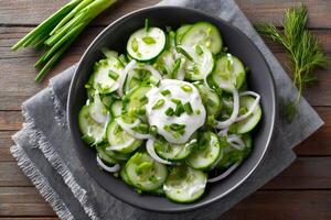 Cucumber salad with sour cream, red onion, chives and dill in a bowl photo