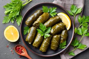 Delicious dolma with lemon and parsley garnished on dark plate photo