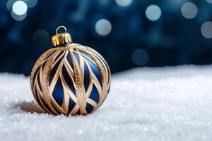 Elegant blue and gold christmas ornament resting on sparkling snow with festive bokeh background photo