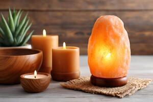 Himalayan salt lamp glowing with burning candles and wooden bowls creating warm atmosphere photo