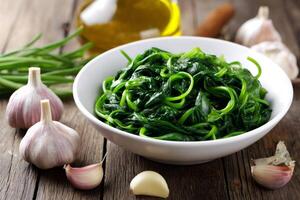 Steamed spinach with garlic and olive oil on rustic wooden table photo