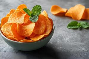 Bowl of Crunchy Potato Chips with Mint Garnish on Rustic Stone Surface photo