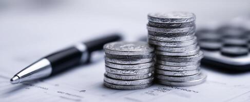 The stack of coins beside a calculator and pen on financial documents. photo