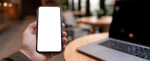 The smartphone in hand showcasing a blank screen in a modern workspace. photo