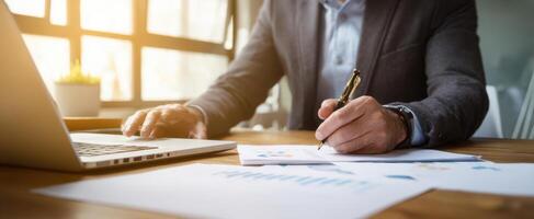 The businessman analyzing financial data while writing notes at his desk. photo