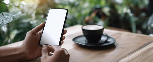 The smartphone held in hands with coffee on a wooden table. photo