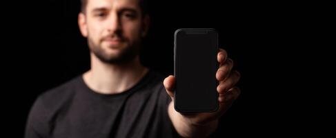 The man holding a smartphone in a dark setting. photo