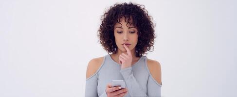 The woman thoughtfully checking her smartphone in a minimalist studio setting. photo